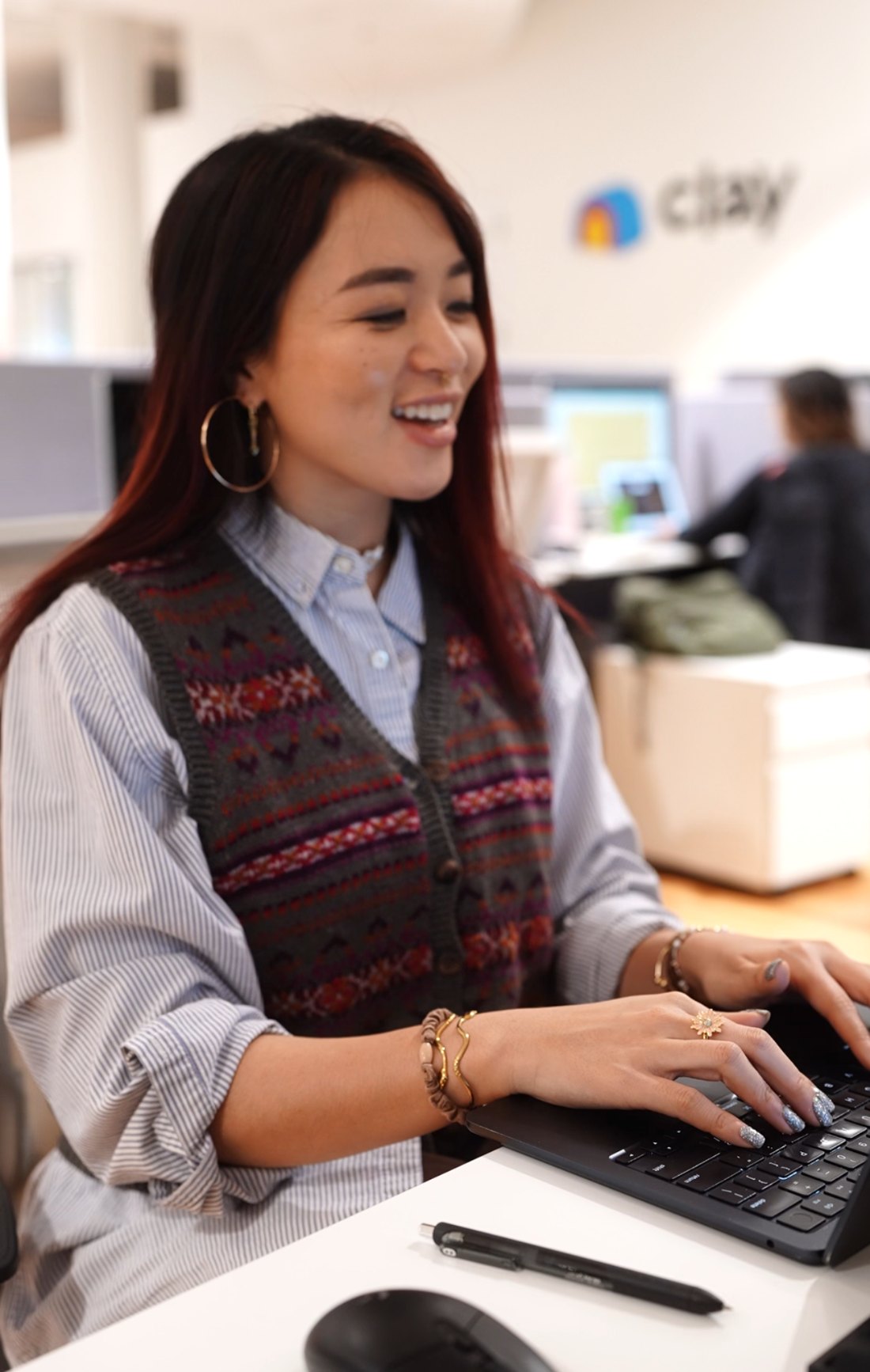 Kara Wang at her desk, mid-laugh, working on a laptop